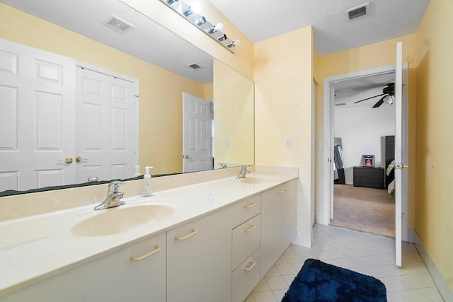 bathroom with tile patterned floors, ceiling fan, vanity, and a textured ceiling