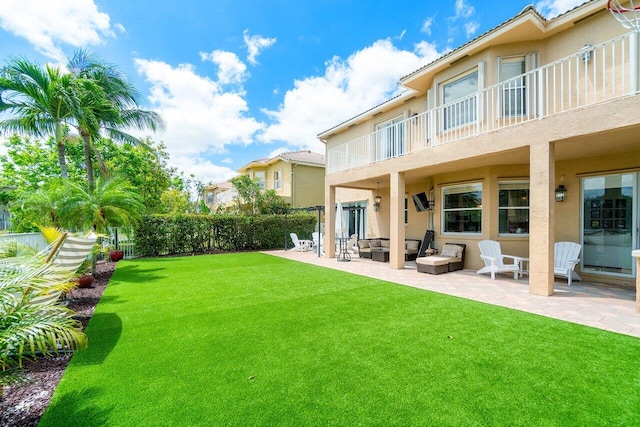 rear view of property featuring a patio, a balcony, and a lawn