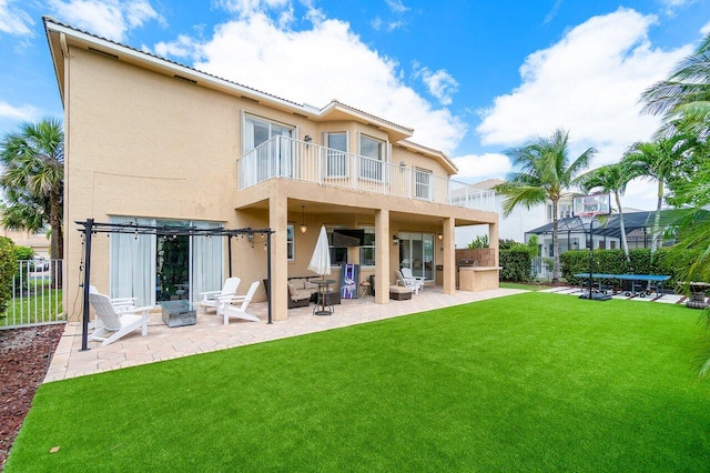 rear view of property featuring a patio, a balcony, and a lawn