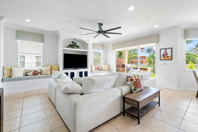 living room featuring built in shelves, ceiling fan, ornamental molding, light tile patterned floors, and a textured ceiling