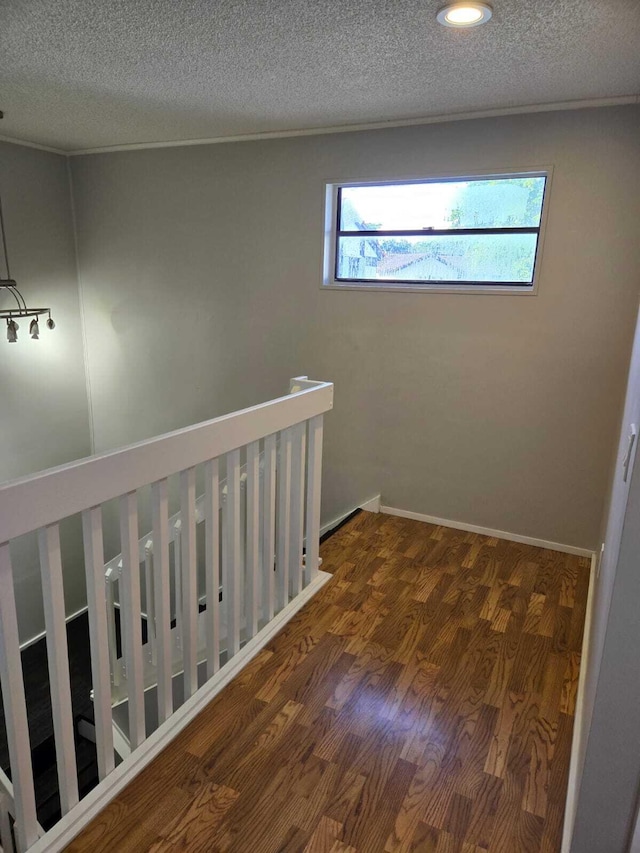 corridor with a textured ceiling, dark wood-type flooring, and a wealth of natural light