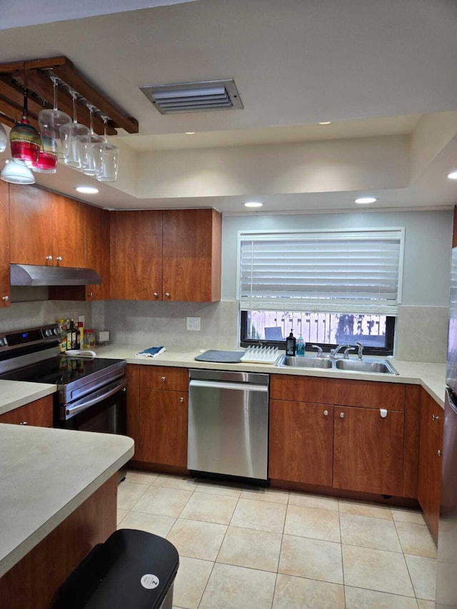 kitchen with sink, hanging light fixtures, stainless steel appliances, decorative backsplash, and light tile patterned floors