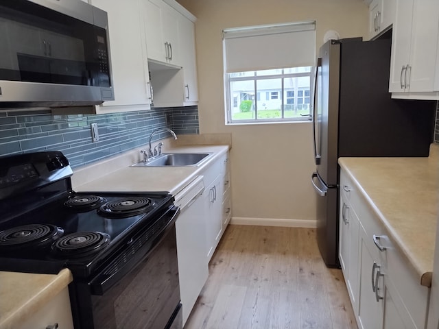 kitchen with sink, tasteful backsplash, light hardwood / wood-style flooring, white cabinetry, and appliances with stainless steel finishes