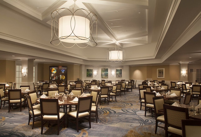 dining space featuring carpet floors, decorative columns, coffered ceiling, ornamental molding, and beamed ceiling