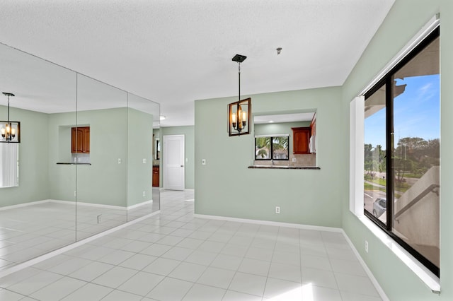 spare room featuring a textured ceiling, a notable chandelier, and light tile patterned floors