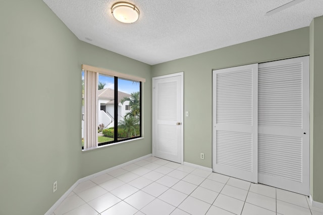 unfurnished bedroom featuring light tile patterned flooring, a textured ceiling, and two closets