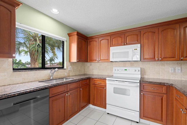 kitchen featuring tasteful backsplash, dark stone counters, a textured ceiling, sink, and white appliances