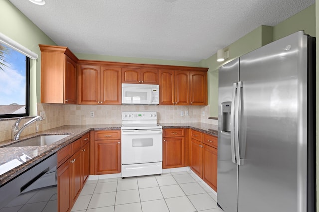 kitchen featuring white appliances, dark stone countertops, sink, and tasteful backsplash