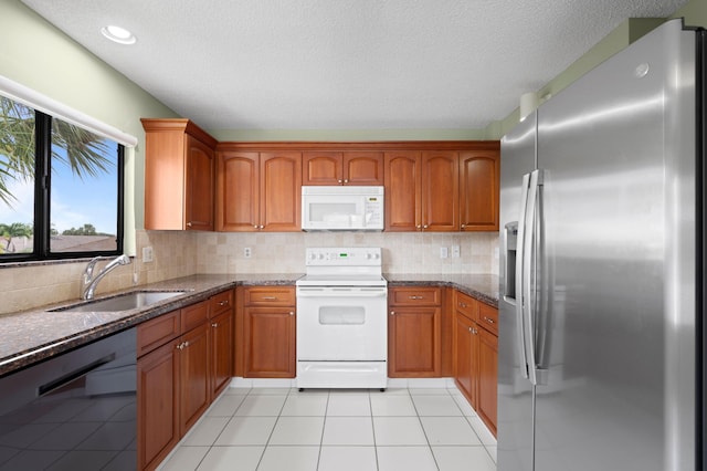 kitchen featuring dark stone counters, white appliances, sink, and decorative backsplash