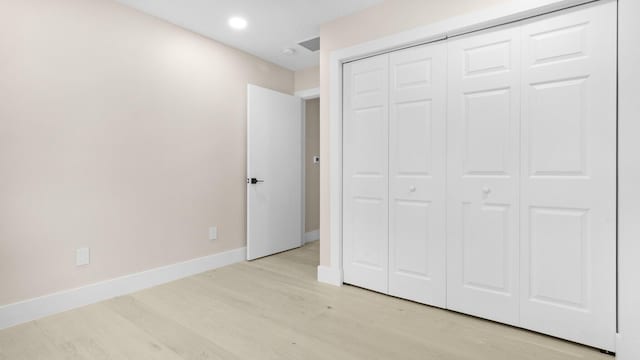 unfurnished bedroom with light wood-type flooring and a closet