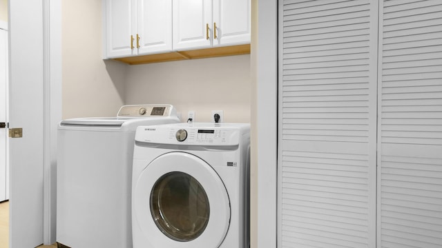 clothes washing area with washing machine and dryer and cabinets