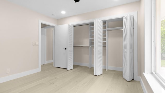 unfurnished bedroom featuring light wood-type flooring and two closets