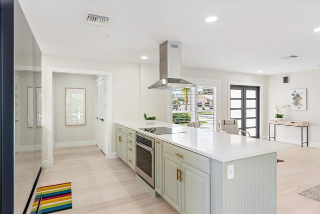 kitchen with black electric cooktop, light hardwood / wood-style floors, oven, and island exhaust hood