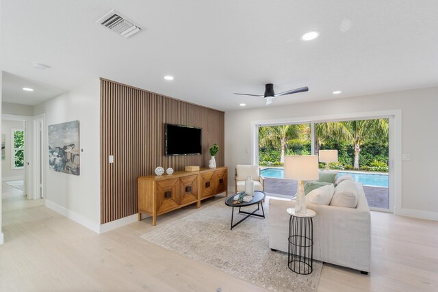 kitchen with range hood, white cabinets, light hardwood / wood-style flooring, a breakfast bar area, and stainless steel fridge