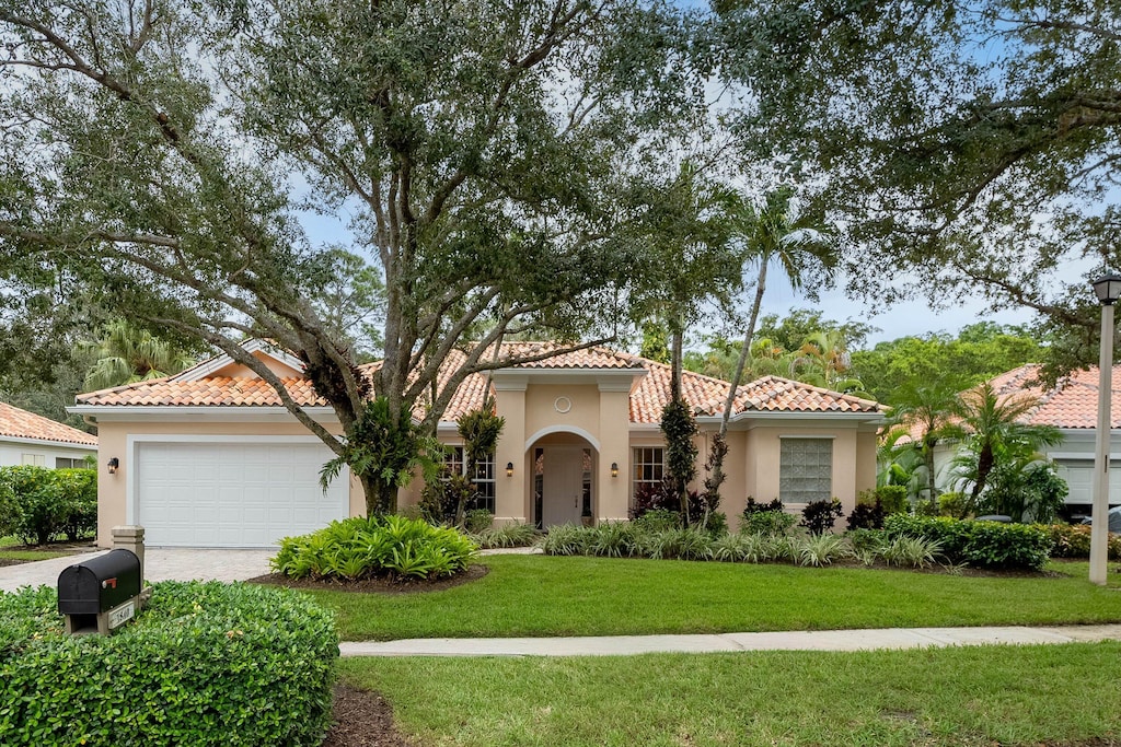 mediterranean / spanish home featuring a front yard and a garage