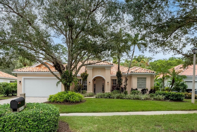 mediterranean / spanish home featuring a front yard and a garage