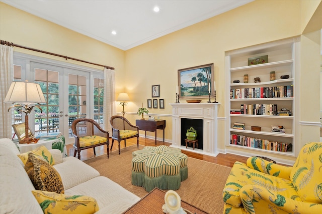 living room with ornamental molding, french doors, built in shelves, and hardwood / wood-style flooring