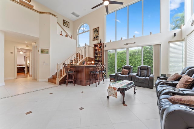 living room featuring a towering ceiling, bar, light tile patterned floors, and ceiling fan