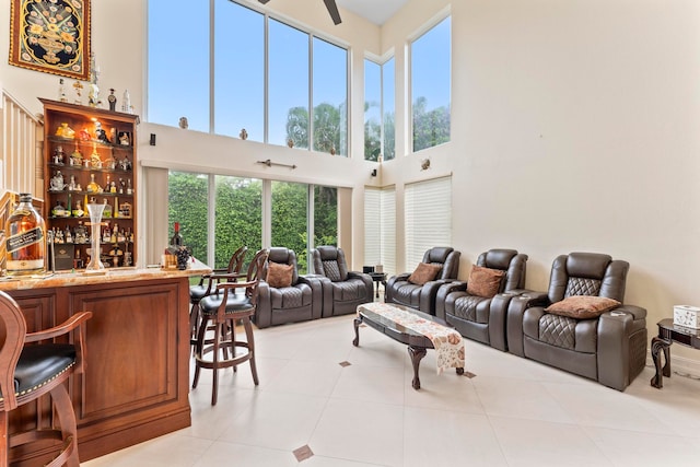 tiled living room featuring a towering ceiling, bar, and ceiling fan