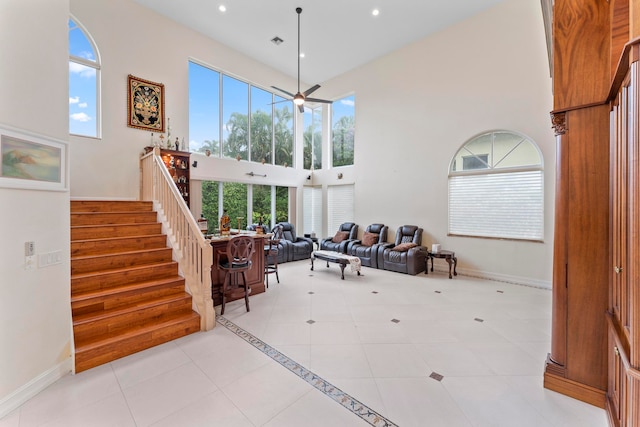 interior space with a towering ceiling, light tile patterned flooring, and ceiling fan