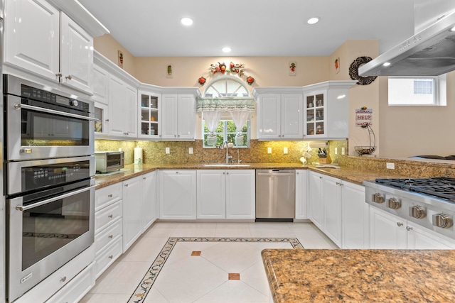 kitchen with sink, backsplash, white cabinetry, stainless steel appliances, and extractor fan