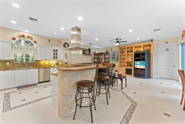 kitchen featuring dishwasher, a kitchen bar, island range hood, white cabinetry, and ceiling fan