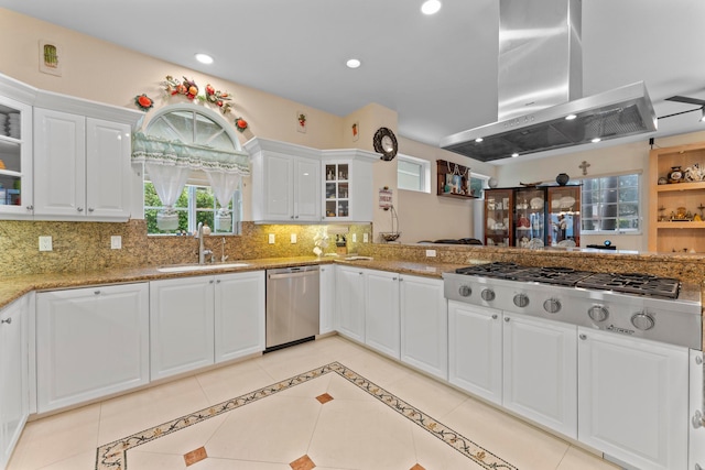 kitchen featuring appliances with stainless steel finishes, sink, island range hood, backsplash, and white cabinetry