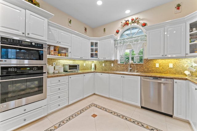 kitchen featuring appliances with stainless steel finishes, white cabinets, sink, and light stone counters