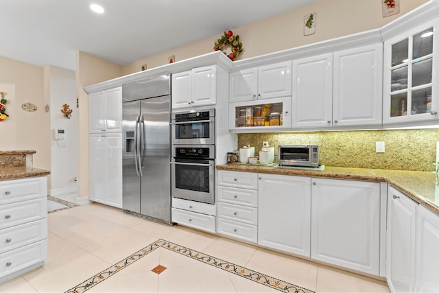 kitchen with white cabinets, tasteful backsplash, stainless steel appliances, and light stone countertops