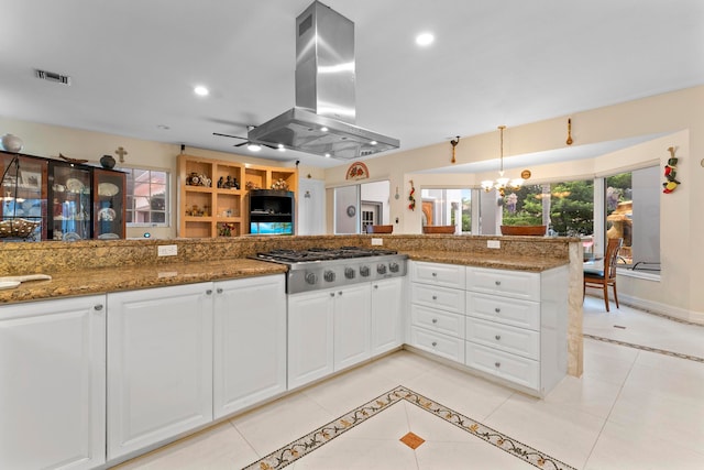 kitchen featuring white cabinetry, stainless steel gas stovetop, island range hood, stone countertops, and pendant lighting