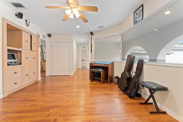 exercise area with light hardwood / wood-style flooring and ceiling fan