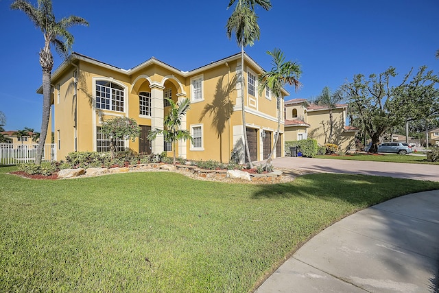 mediterranean / spanish-style home featuring a front lawn and a garage