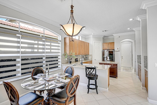 dining room with sink, a textured ceiling, ornamental molding, and light tile patterned floors