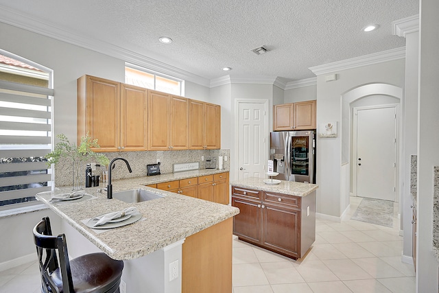 kitchen featuring stainless steel fridge, tasteful backsplash, a kitchen island, crown molding, and sink