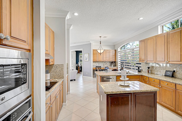 kitchen featuring a kitchen island with sink, stainless steel appliances, ornamental molding, pendant lighting, and light stone counters