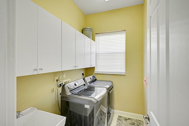 clothes washing area with washing machine and dryer, sink, and cabinets