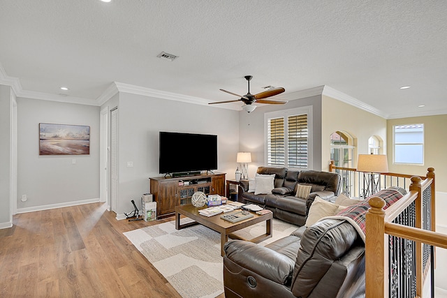 living room featuring light hardwood / wood-style flooring, ornamental molding, a textured ceiling, and ceiling fan