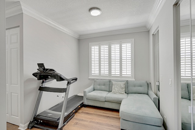 workout room featuring a textured ceiling, crown molding, wood-type flooring, and plenty of natural light