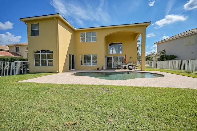 rear view of property with a patio area, a lawn, and a fenced in pool