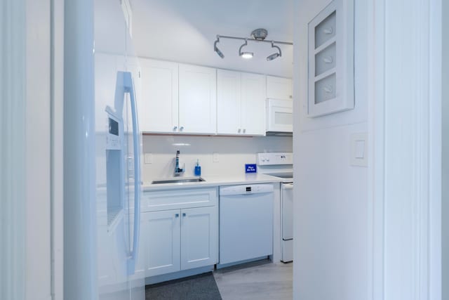 kitchen featuring sink, white cabinetry, light hardwood / wood-style flooring, and white appliances