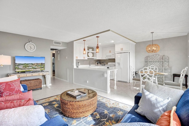 living room featuring light tile patterned floors, a textured ceiling, a chandelier, and sink