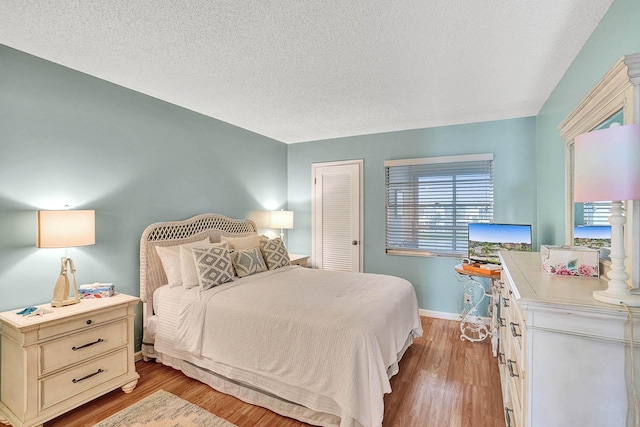 bedroom with a textured ceiling and light hardwood / wood-style floors