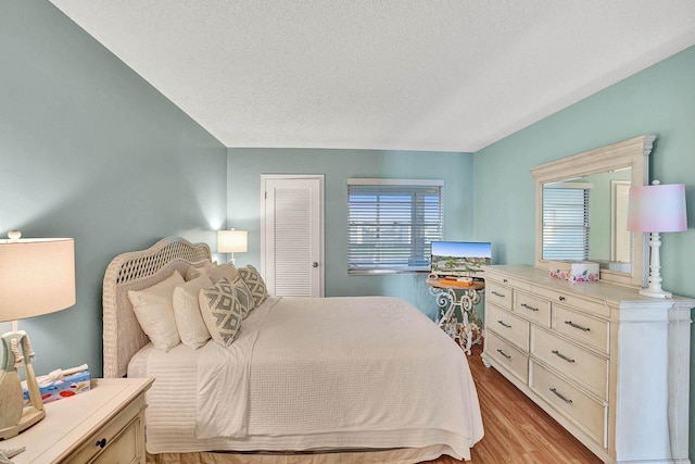 bedroom with a closet, light hardwood / wood-style floors, and a textured ceiling