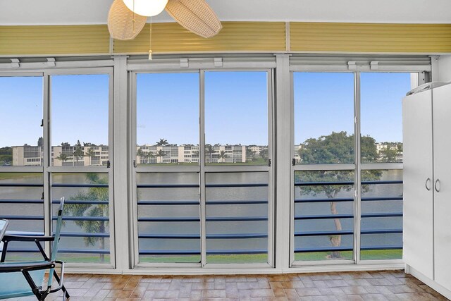 unfurnished sunroom featuring ceiling fan, a water view, and plenty of natural light