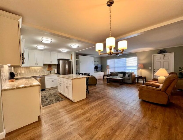 kitchen featuring hanging light fixtures, light hardwood / wood-style flooring, white cabinetry, stainless steel appliances, and a center island