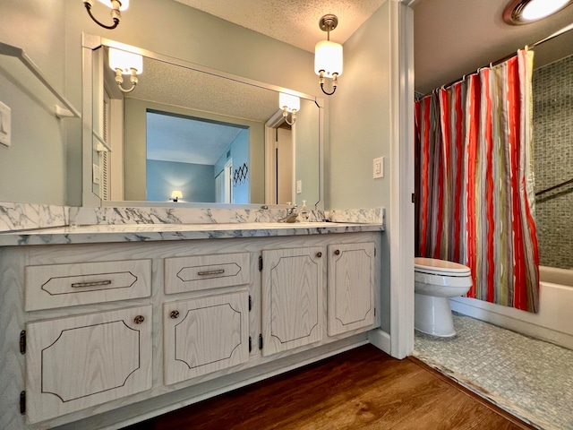 full bathroom with hardwood / wood-style floors, vanity, shower / bath combo, toilet, and a textured ceiling