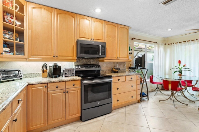 kitchen featuring appliances with stainless steel finishes, light stone counters, a textured ceiling, and light tile patterned floors