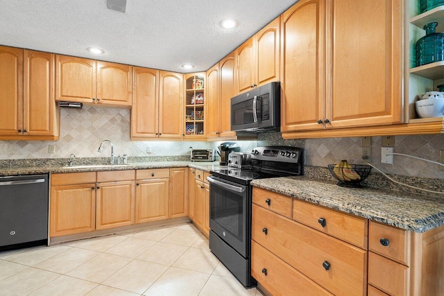 kitchen featuring dark stone counters, sink, light tile patterned flooring, appliances with stainless steel finishes, and a textured ceiling