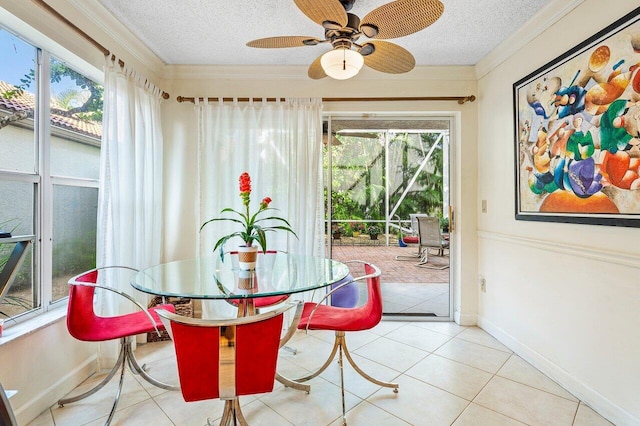 tiled dining space with ceiling fan, a textured ceiling, and ornamental molding