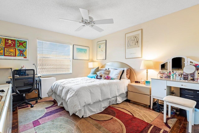 bedroom with a textured ceiling, wood-type flooring, and ceiling fan